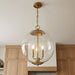 Gold pendant light with clear glass shade hanging in a kitchen.