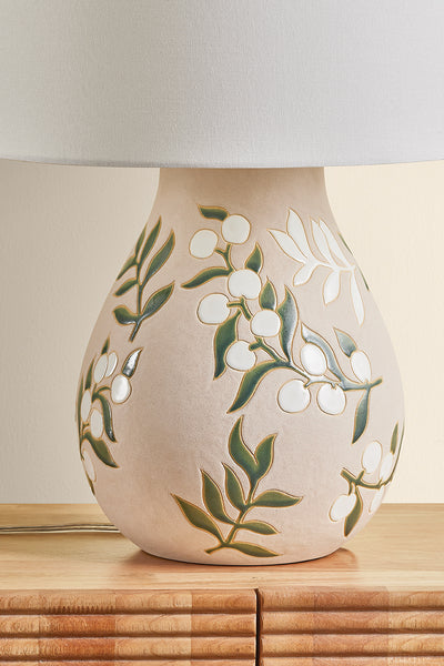 Ceramic lamp with leaf design on a wooden surface