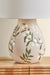 Ceramic lamp with leaf design on a wooden surface