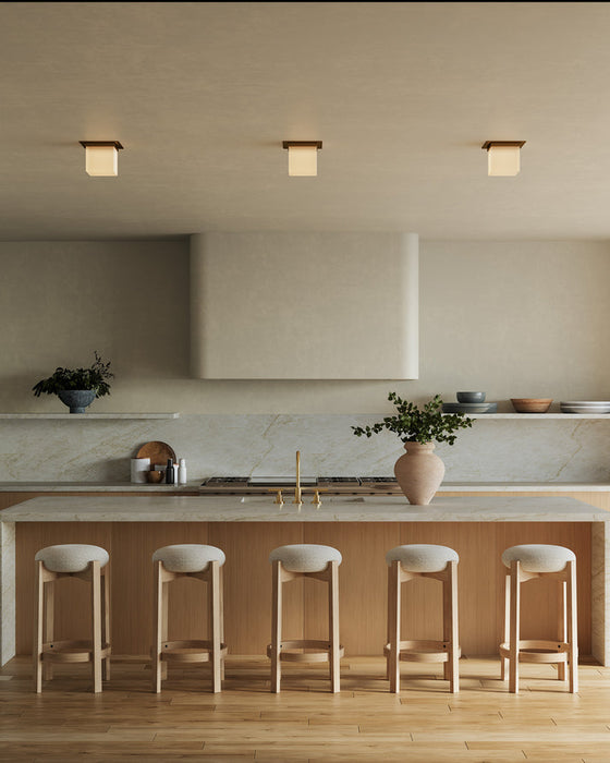 Three square alabaster flush mounts hang over a modern kitchen island
