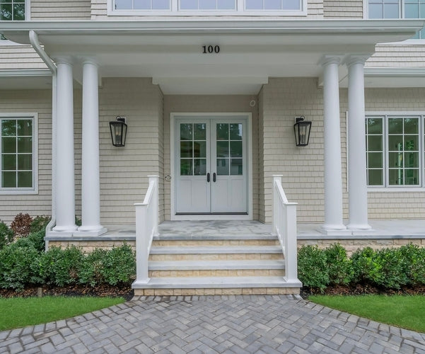 Front of a house with white columns, steps, and a gray driveway.