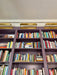 Purple bookshelf filled with books and gold light fixtures on a white wall.