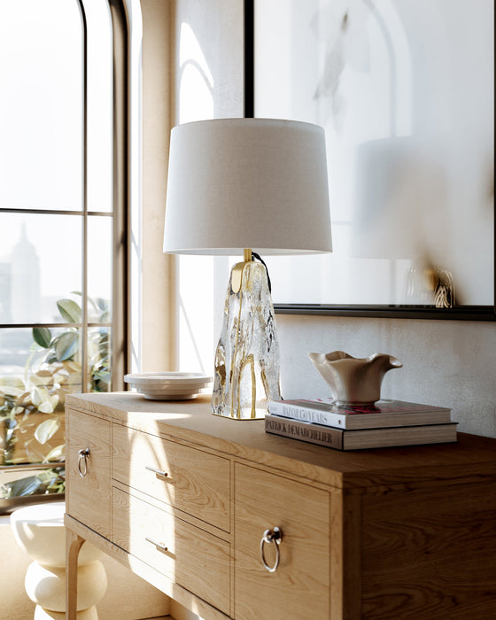 Wooden dresser with glass-base table lamp, decorative bowl, books, and ceramic bird near a sunlit window.
