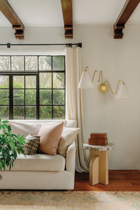 Living room with a white sofa, decorative pillows, a small table, and a wall sconce.