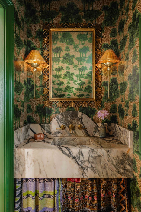 Decorative bathroom with marble sink, gold fixtures, and patterned wallpaper.
