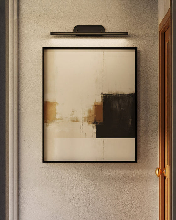 Black picture light hangs above an artwork piece on a wall