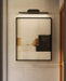 Black picture light hangs above an artwork piece on a wall