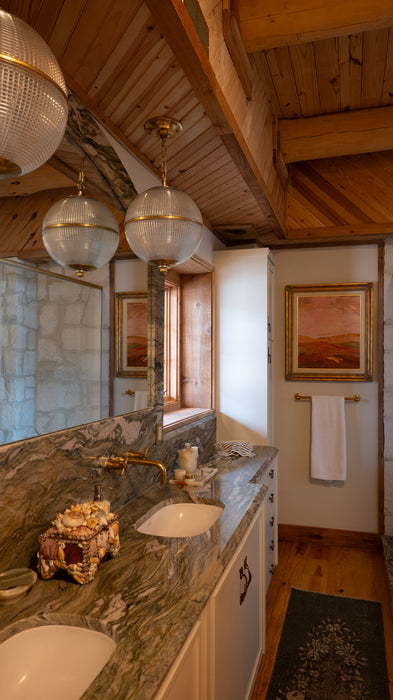 Bathroom with marble countertop, large mirror, and wooden ceiling.
