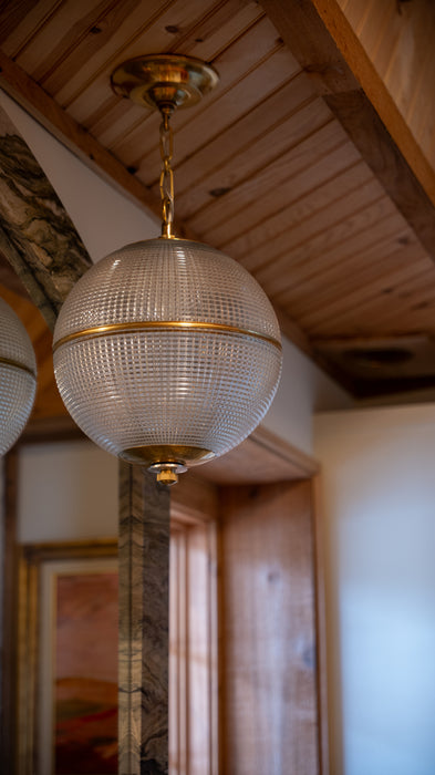 Decorative ceiling light fixture in a room with wooden beams and a painting.