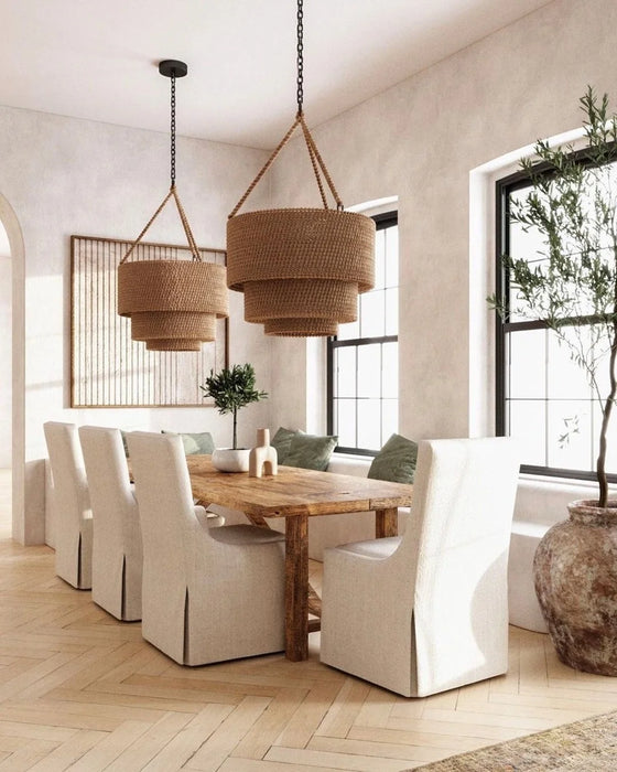 Dining room with wooden table, white chairs, and wicker pendant lights.