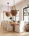 Dining room with wooden table, white chairs, and wicker pendant lights.
