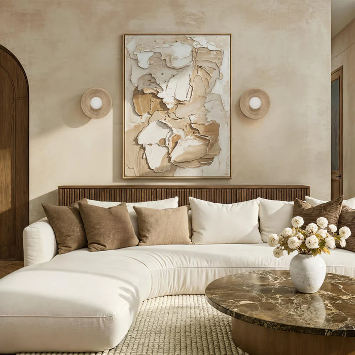 Modern neutral-toned living room with curved white sectional sofa, abstract wall art, and matching stone wall sconces.