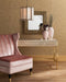 Pink armchair and console table with decorative mirror and vases against a gold patterned wall.