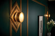 Decorative wall sconce with geometric design on a dark green wall.