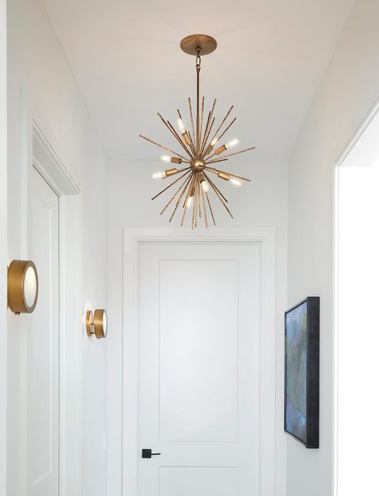 Modern gold chandelier in a hallway with white walls and a door.