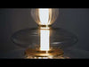 Pendant light fixture featuring a stacked, totem-like composition of alternating clear optic and smoked glass shades. The layered glass elements vary in transparency and texture, creating depth and visual contrast. At the center, a single vertical LED tube serves as the core light source, emitting a steady glow that passes through each layer, producing a warm, diffused illumination