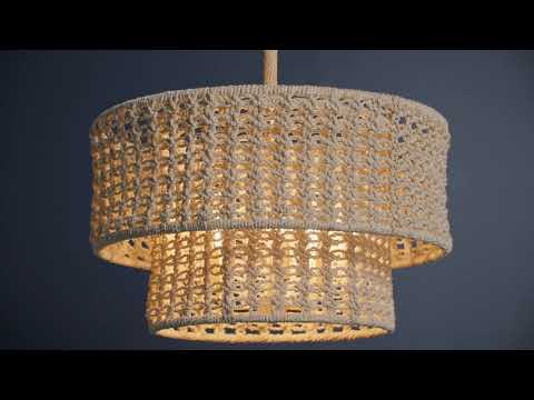 Two-tier pendant light fixture handwoven from bleached abaca rope in a macramé-like pattern. The layered design creates a soft, draped silhouette with visible knots and texture, giving it a relaxed, bohemian style. Light filters through the woven material, casting a warm, diffused glow and subtle patterned shadows.