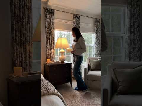 A woman swaps out her bedside table lamp for a new white lamp