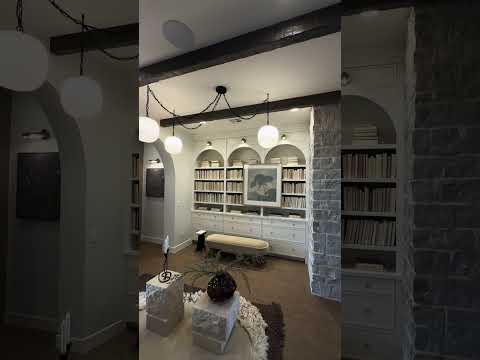 Room with a library wall and a large three light swagged chandelier hanging from ceiling