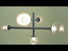 Chandelier-style light fixture combining bold, structured lines with soft visual elements, featuring large clear glass orbs that fully expose the light source. The frame is finished in a cool slate blue, creating contrast with an aged brass central rod. The glass orbs allow light to shine brightly and evenly, while the mixed finishes add depth and a modern, balanced aesthetic.